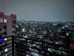 Ein Nachtblick auf die Stadt vom Balkon mit Geländer.