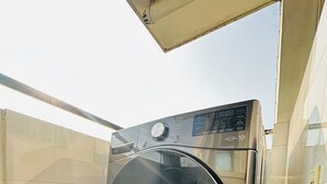 A compact, modern washing machine in a small, tiled laundry room with a slanted ceiling. - 2-bedroom, 14th floor apartment in Nakkhu, Lalitpur nearby Medi-Citi hospital. (Lalitpur)