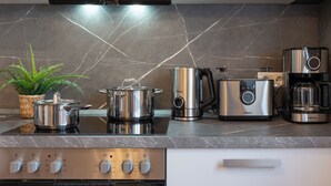 Eine moderne Küche mit Herd, Töpfen, Kaffeemaschine und Mixer.