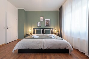 A neatly made bed with two pillows, a bedside table with a lamp, and framed pictures on the wall.