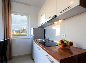 A compact kitchen with a window, a bowl of fruit on the counter, and a view of the outside. - One-bedroom apartment Grey Goose 7 with private balcony (Novalja)
