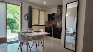 A compact kitchen with a dining area, a large mirror, and a view of the outdoors.