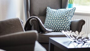 Eine gemütliche Sitzecke mit grauem Sofa, einem gemusterten Kissen und einem kleinen Tisch mit einer Dekoration.