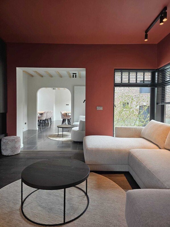 A modern living room with a sectional sofa, a round coffee table, and a dining area with chairs and a table.