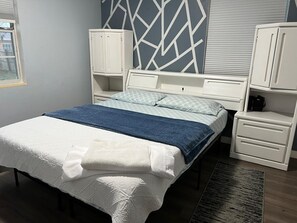 A bedroom with a bed, nightstands, a dresser, and a geometric-patterned wall. -  Welcome to Casa Alafia at Riverview. (Riverview)