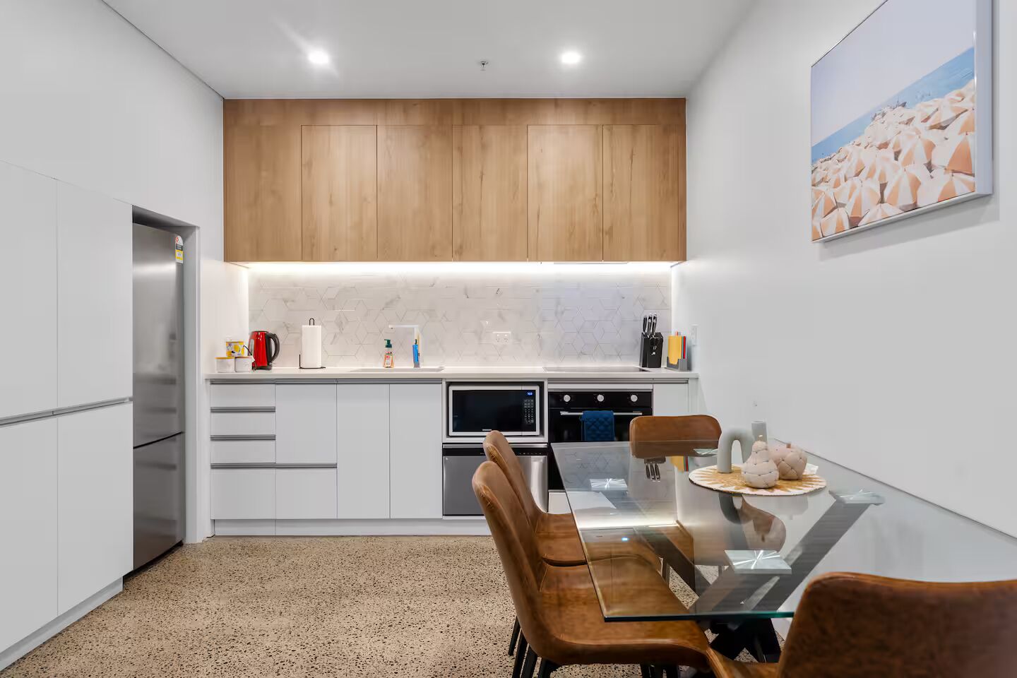 Een moderne keuken met witte kasten, een houten aanrecht en een glazen eettafel.