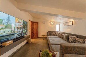 A living room with a flat-screen TV, a sofa, a wall-mounted light, and a 'COME IN CLOSER' sign. - Staymaster Sea La Vie  (Nerul)