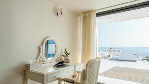Ein Zimmer mit weißem Schminktisch, einem Laptop, einem Spiegel und einem Topf mit Pflanze.