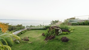 Ein gepflegter Garten mit einem Weg, verschiedenen Pflanzen und Meerblick.