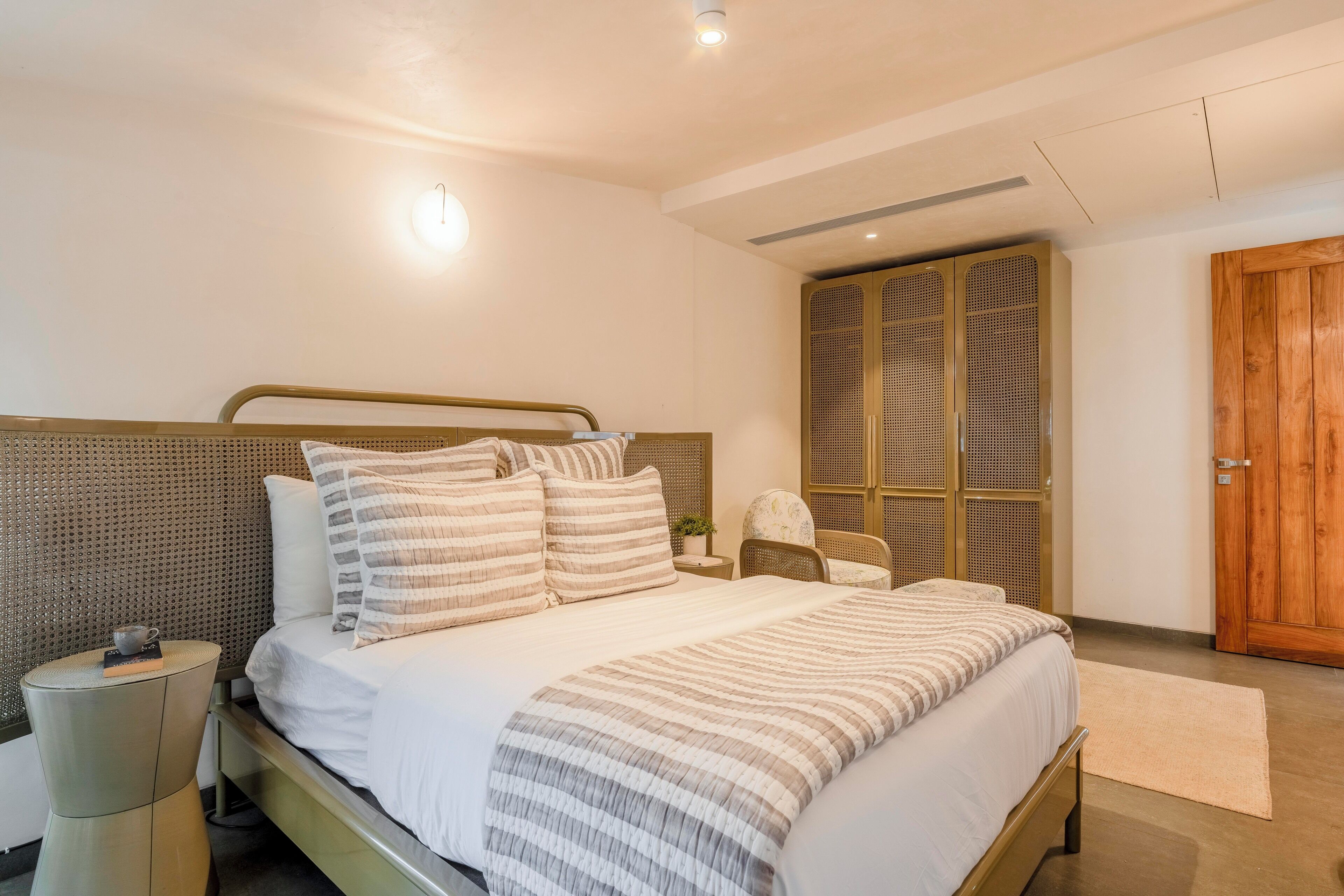 Un dormitorio moderno con una cama grande, una mesita de noche, una silla y un armario.