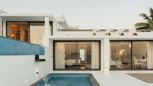 Ein modernes Haus mit Schwimmbad, großen Glasfenstern und einem Balkon.