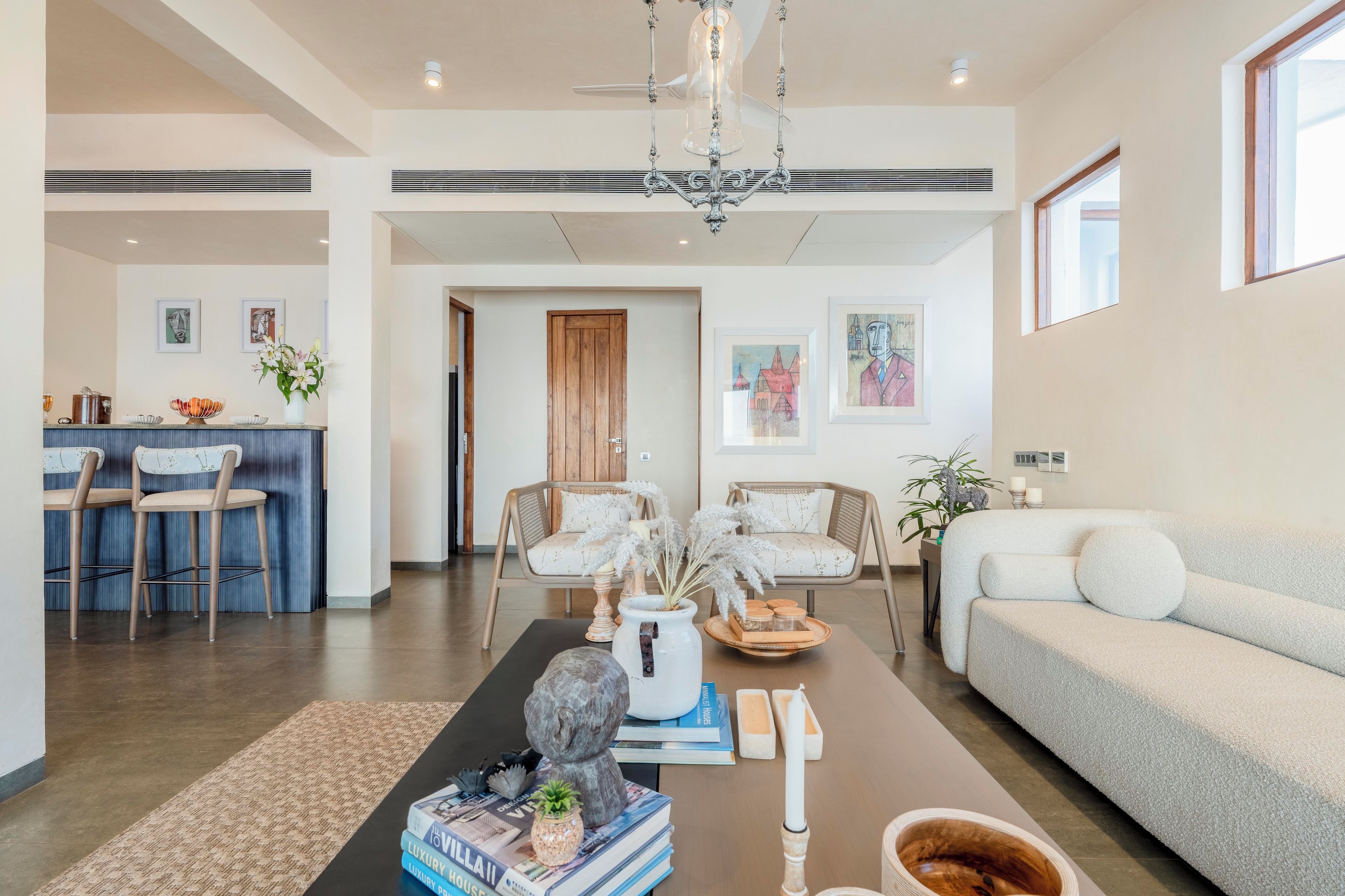 A spacious living area with a sofa, chairs, a coffee table, and artwork on the walls.