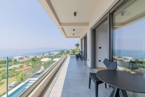 Ein Balkon mit Glasgeländer mit Blick auf eine Stadtlandschaft und ein Gewässer.