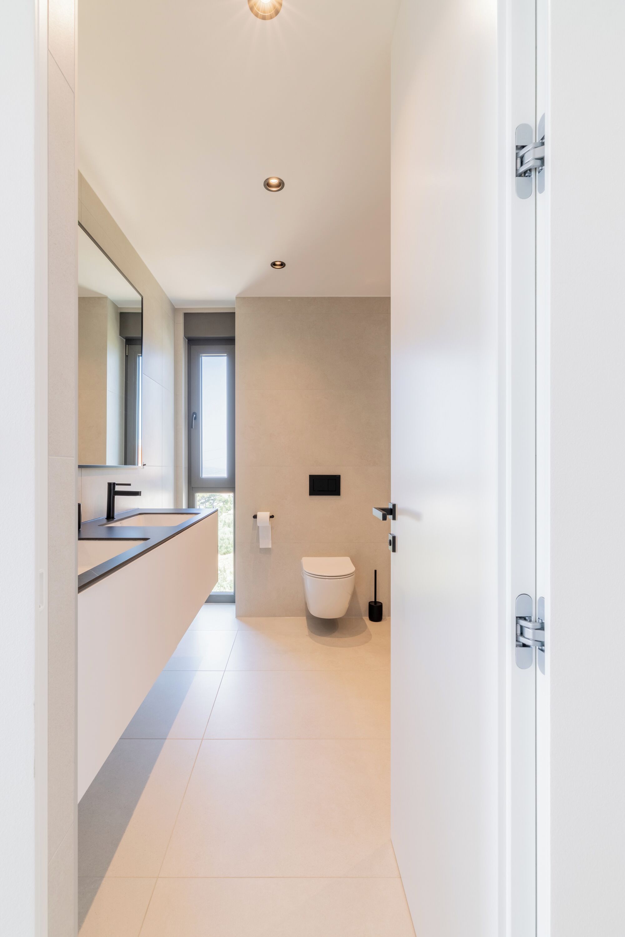 Un baño moderno con un espejo grande, un lavamanos y un inodoro.