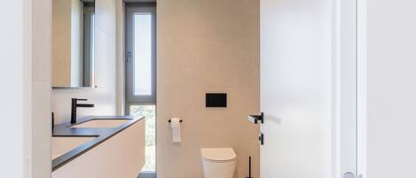 Un baño moderno con un espejo grande, un lavamanos y un inodoro.