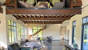 Un vaste espace de vie agrémenté de canapés en cuir, d’une table basse ronde et d’un escalier menant à un niveau supérieur.