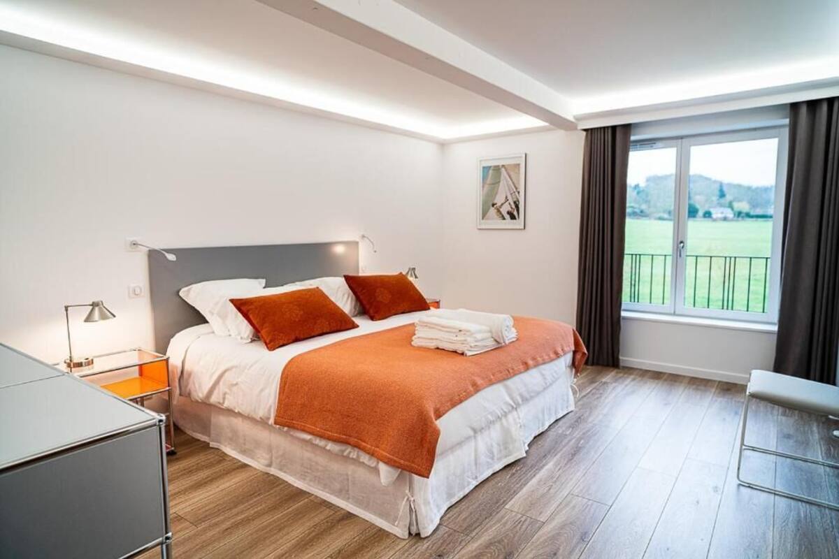 A modern hotel room with a bed, a desk, a chair, and a large window with a view.