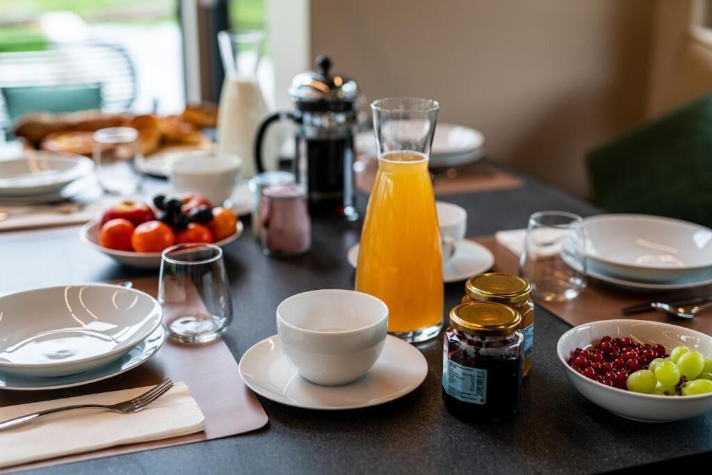A breakfast table set with plates, bowls, a pitcher of orange juice, and various condiments.