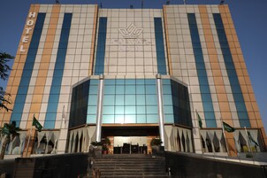 Um hotel com fachada moderna, grandes janelas de vidro e uma entrada destacada com degraus.