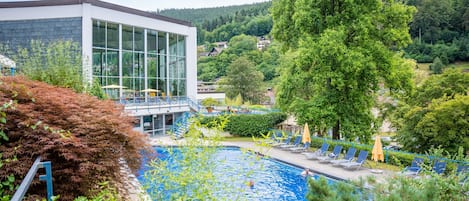 A swimming pool with lounge chairs and a modern building with large windows.