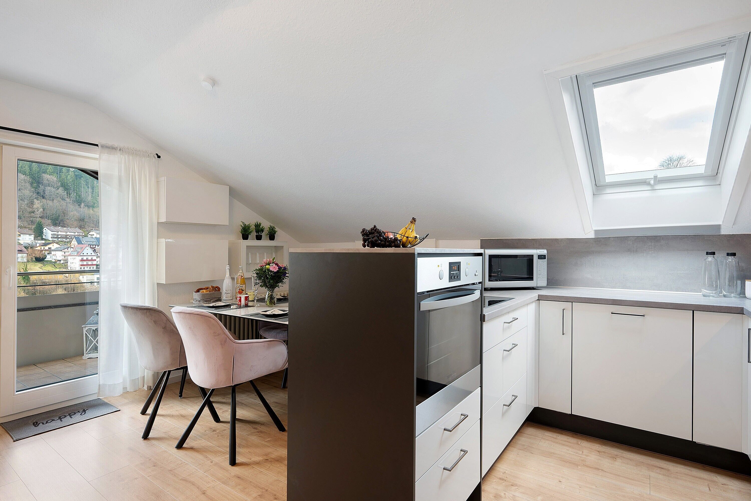Una cocina moderna con comedor, vistas por la ventana y un balcón.