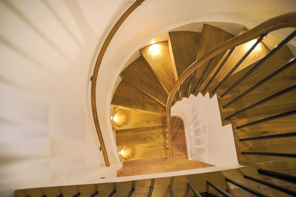 A spiral staircase with wooden steps and a white handrail.