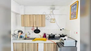 A compact kitchen with wooden cabinets, a sink, a stove, and a toaster. - Quantity studio in Ngara, 3mins drive to Nairobi Cbd (Nairobi)