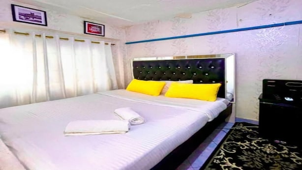 A hotel room with a bed, a headboard, a window with curtains, a wall-mounted TV, and a trash bin. - Quantity studio in Ngara, 3mins drive to Nairobi Cbd (Nairobi)