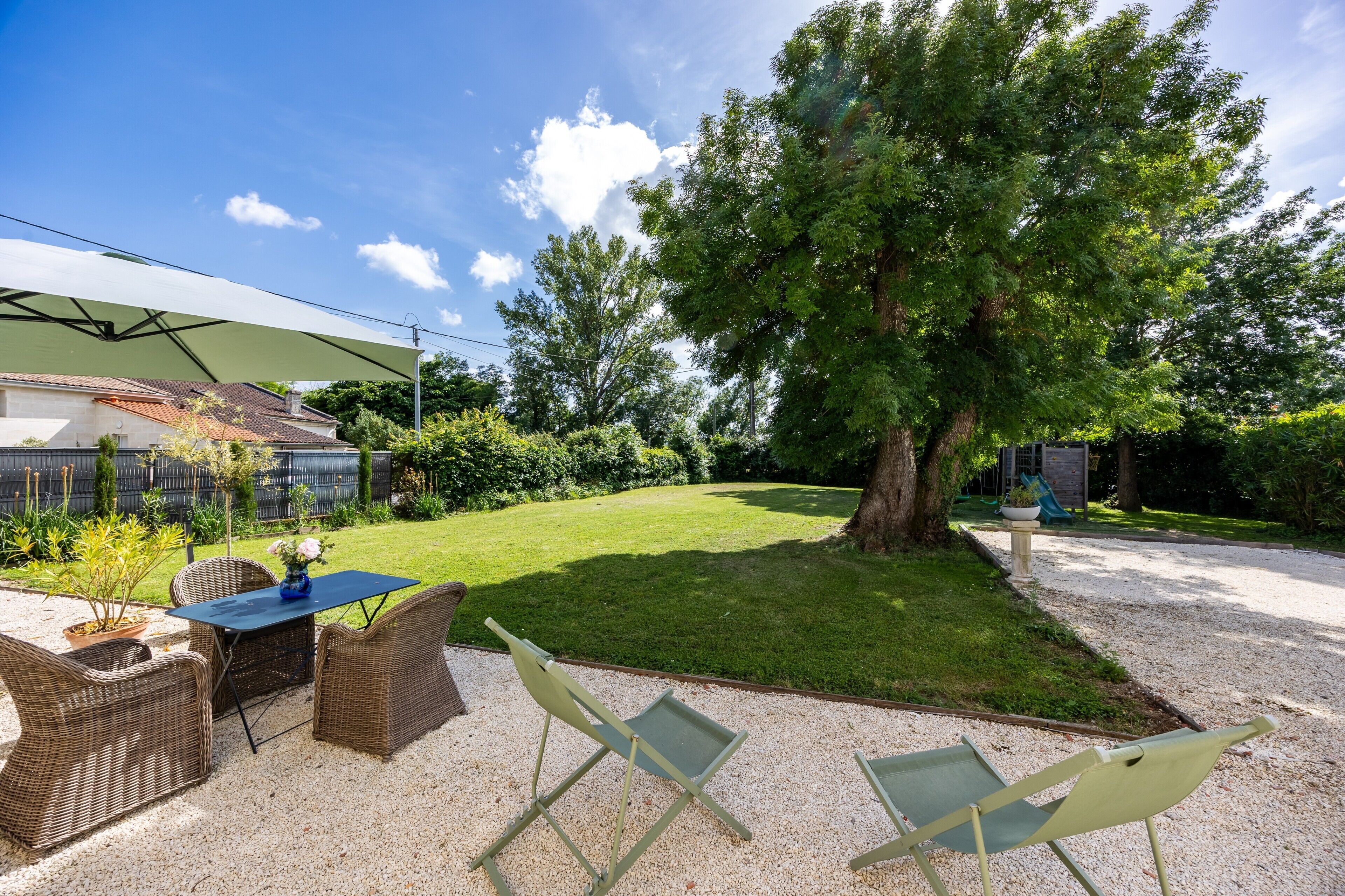 Eine Terrasse mit Korbmöbeln, einem Tisch und einem Blumentopf.
