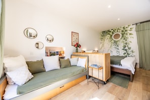 Ein gemütlicher Raum mit Schlafsofa, Tisch, Bett und einem Spiegel an der Wand.