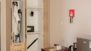A room with a wooden ceiling, a wardrobe with open doors, a desk with a kettle, and a refrigerator with fruit magnets. - Spacious Junior Suite near UN Nairobi, Cozy Stead Haven House (Nairobi)