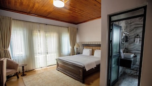 A hotel room with a wooden ceiling, a bed with white linens, a sitting area with a chair, and a bathroom with a marble wall and sink. - Spacious Junior Suite near UN Nairobi, Cozy Stead Haven House (Nairobi)
