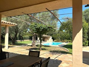 Un patio cubierto con piscina, mobiliario exterior y una pérgola.