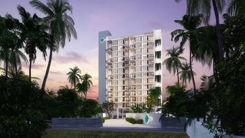 A modern multi-story hotel with a grid-like facade, surrounded by palm trees and greenery.