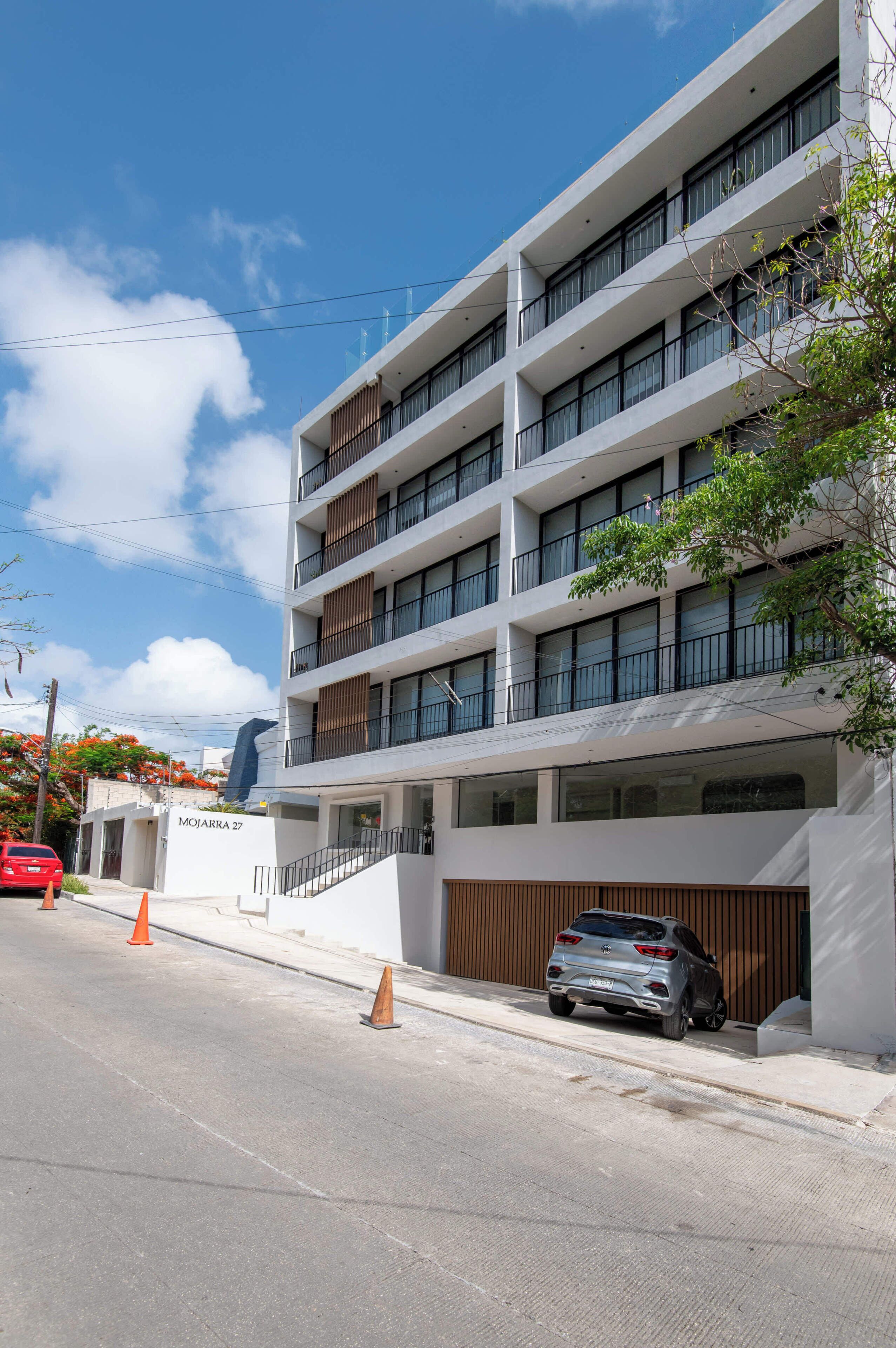 Un edificio de varios pisos con un diseño arquitectónico moderno, que cuenta con balcones y ventanas amplias.