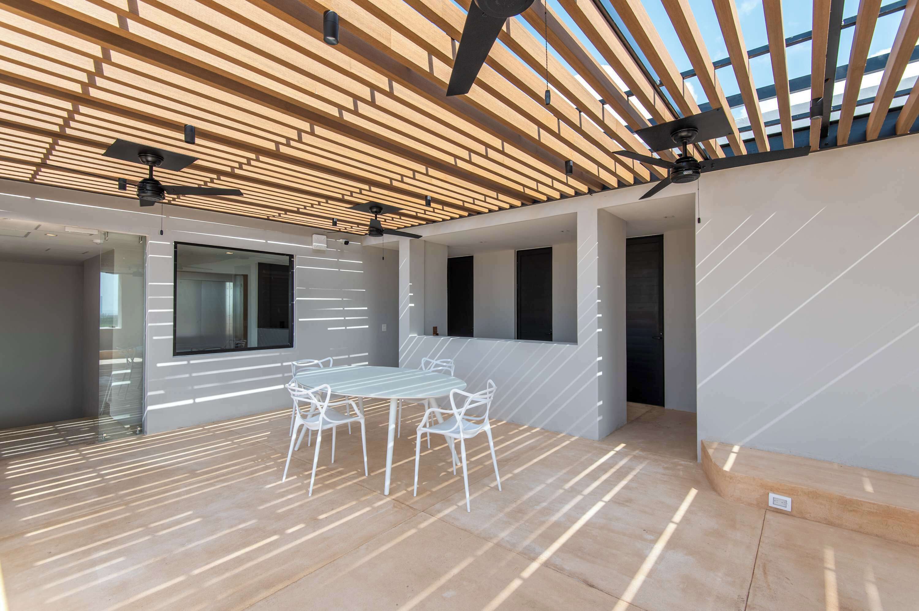 A modern interior with a wooden ceiling, a round table with chairs, and large windows.