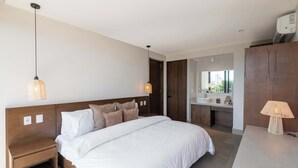 A modern hotel room with a large bed, bedside tables, a vanity with a mirror, and a lamp. - Mojarra 27: Apt. with Balcony & King Bed (Cancún)