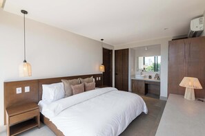 Ein modernes Hotelzimmer mit einem großen Bett, Nachttischen, einem Schminktisch mit Spiegel und einer Lampe.
