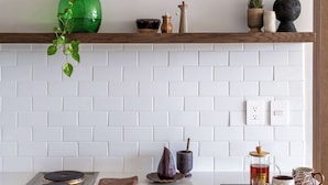 A kitchen with white subway tiles, a wooden countertop, and a variety of kitchen items including a green vase, a coffee pot, and a teapot. - Mojarra 27: Apt. with Balcony & King Bed (Cancún)