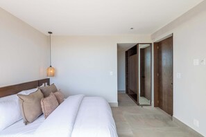 A bedroom with a large bed, a bedside lamp, and a wardrobe. - Mojarra 27: Cozy Apartment with Balcony (Cancún)