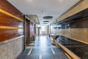 Un couloir d’hôtel avec un sol à motifs, un comptoir de réception et un mur recouvert de carreaux.