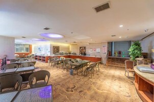 Un vestíbulo de hotel con mostrador de recepción, zona de estar y una escalera que sube a un nivel superior.