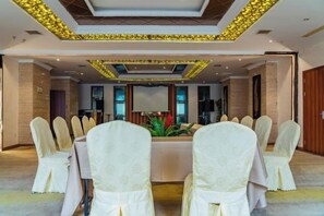 Un salón de conferencias con una larga mesa, sillas y un techo decorativo.