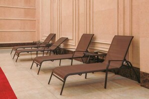 Une rangée de fauteuils confortables est disposée le long d’un mur, et un tapis rouge mène jusqu’à eux.
