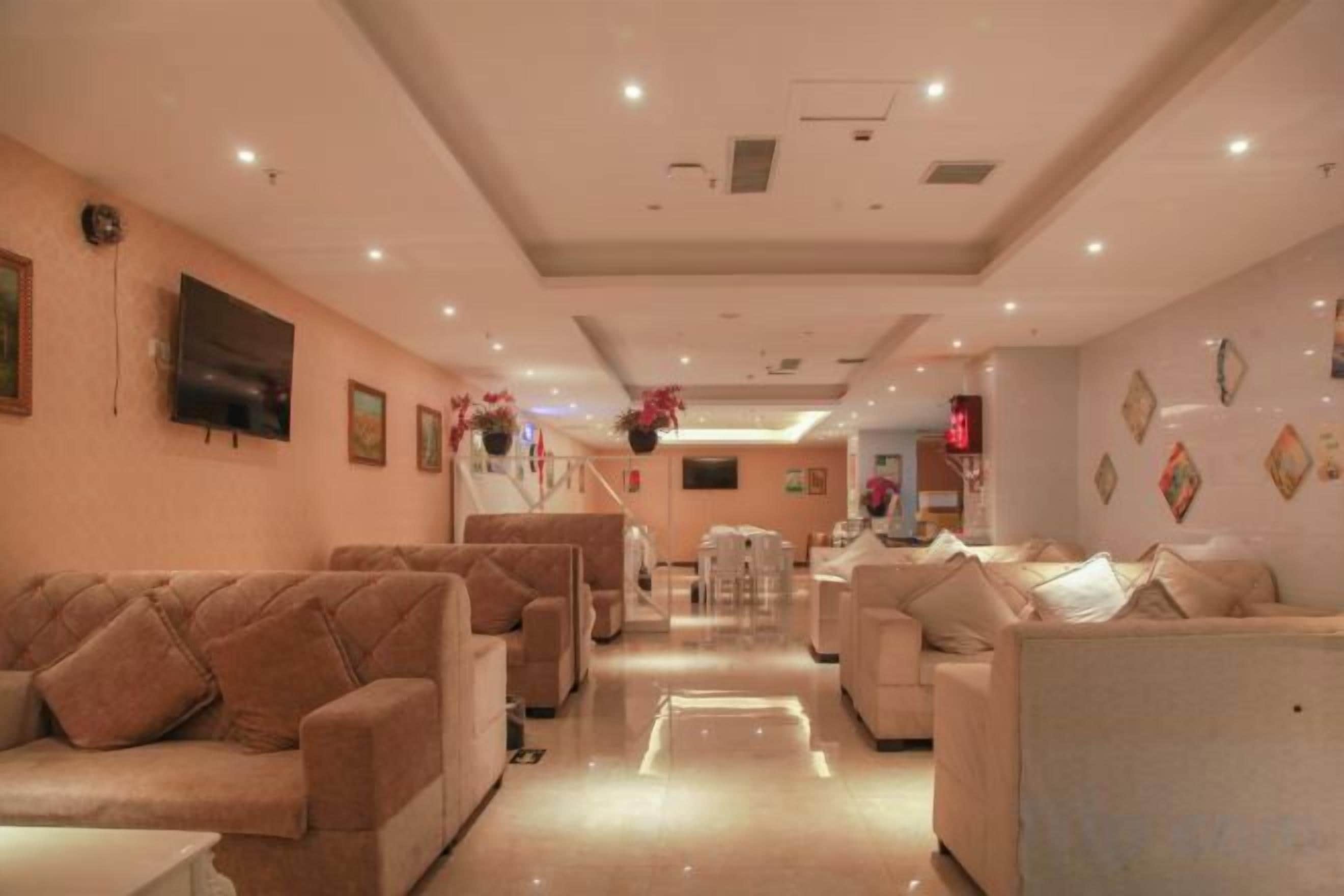 A hotel lobby with sofas, a TV, and a reception desk.