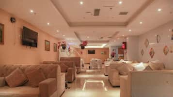 A hotel lobby with sofas, a TV, and a reception desk.