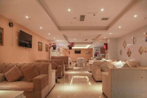 Un vestíbulo de hotel con sofás, televisor y mostrador de recepción.