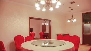 A conference room with a round table, red chairs, and a chandelier.