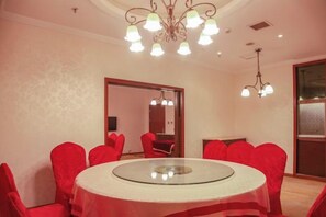 A conference room with a round table, red chairs, and a chandelier.