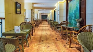 A hotel corridor with wicker furniture, a patterned carpet, and framed artwork on the walls. - Anshun Kaixuan Hotel (Nanma Plaza) (Anshun)